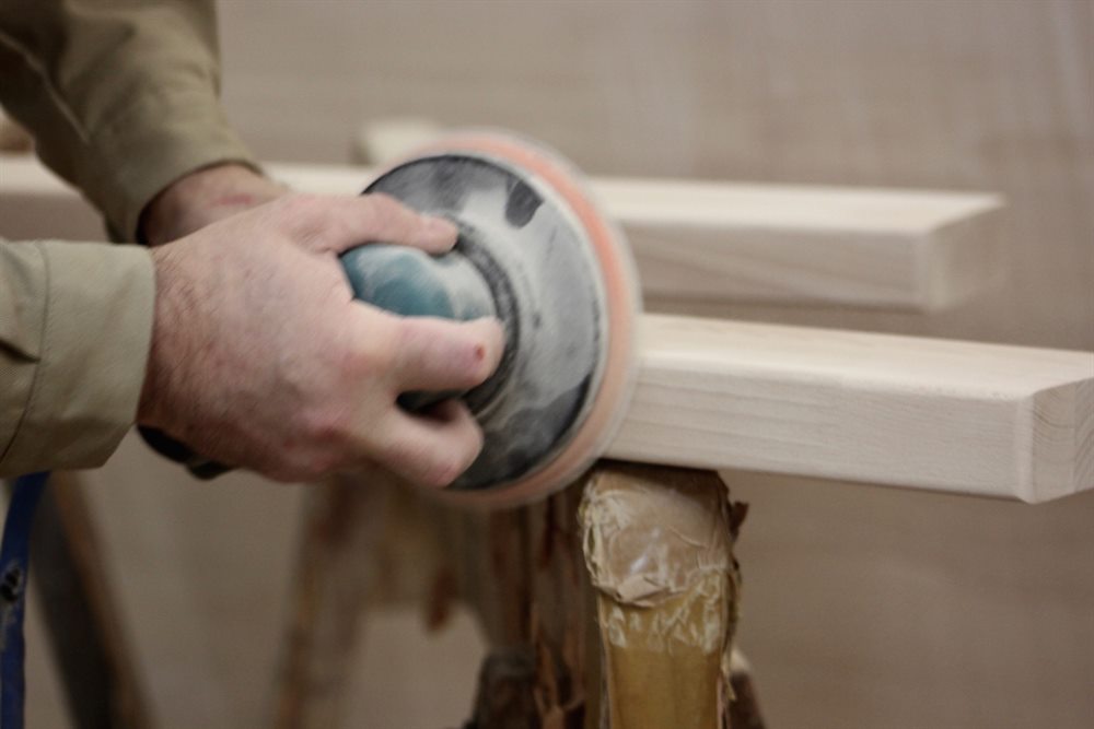 Detailarbeit von Hand an einer Massivholzstufe in der Werkstatt von Stöver Treppenbau