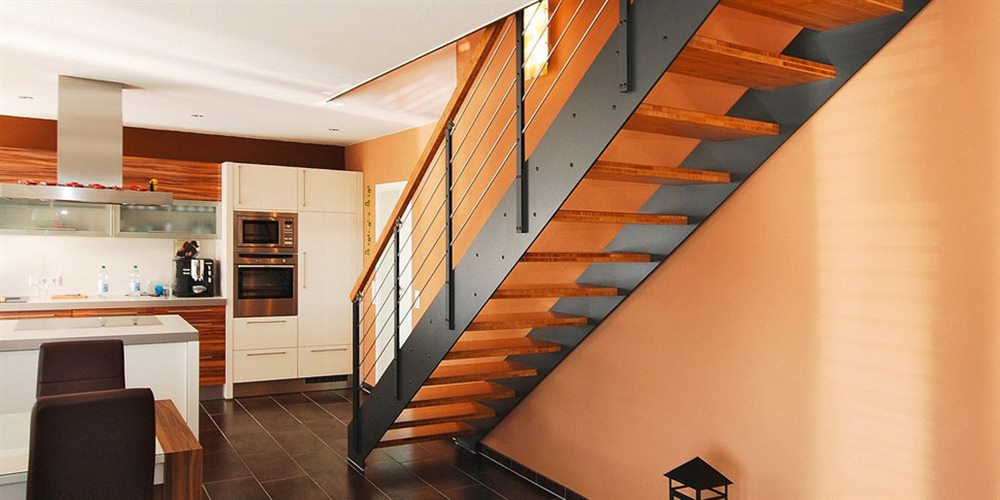 Warme Holztreppe mit Lattengeländer neben offener Wohnküche